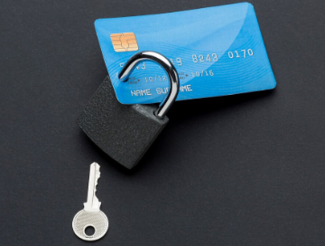 A blue credit card with a padlock and key placed on a dark surface.